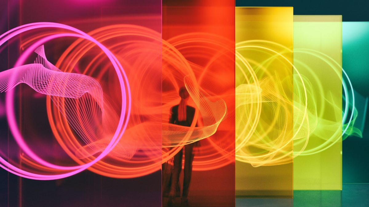 A person standing among glass walls illuminated by glowing rings. All objects in the scene are 3D